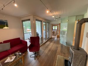 Wohnzimmer des Appartements mit Kaminofen, Sofa und Zugang zum Balkon