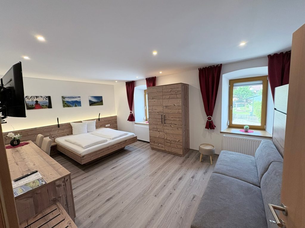 Das neu gestaltete Familienzimmer der Pension Taurer mit Doppelbett, Schlafcouch und heller Holzeinrichtung
