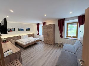 Das neu gestaltete Familienzimmer der Pension Taurer mit Doppelbett, Schlafcouch und heller Holzeinrichtung