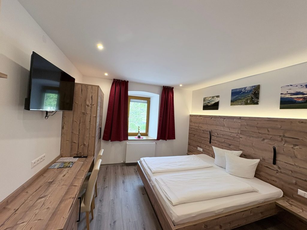 Schlafbereich im neuen Familienzimmer mit Doppelbett und Holz-Kopfteil